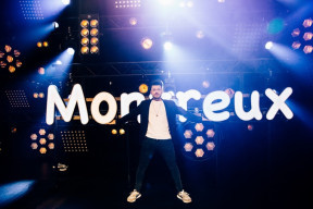 Kev Adams devant le logo lumineux sur la scène du festival de Montreux