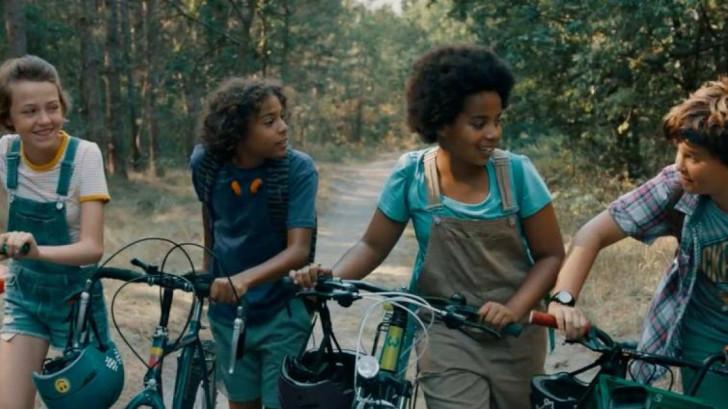 Les quatre enfants marchant dans la forêt, un vélo à la main