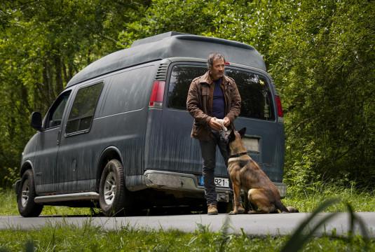 Photo de Bruno Debrandt devant le van bleu et accompagné d'un chien