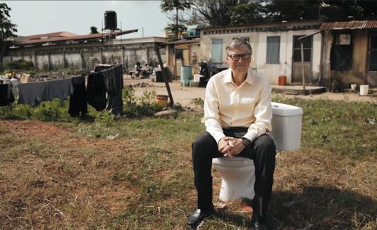 Photo de Bill Gates assis sur un toilette posé devant une maison