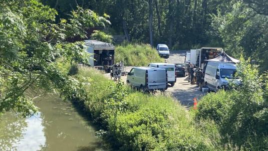 Des camions de tournage installés en bordure d'un canal