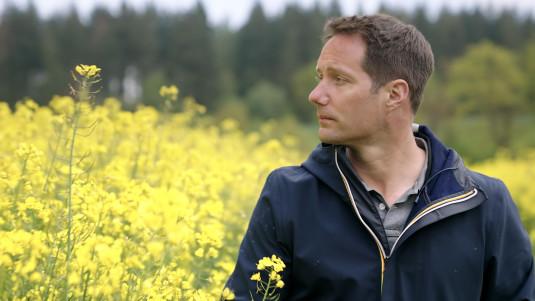 Thomas Pesquet pris de profil devant un champ de colza