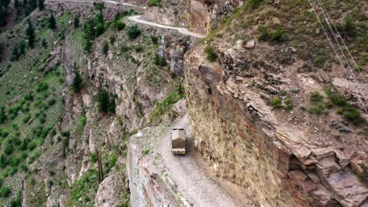 Photo d'une route non bîtumée longeant la montagne