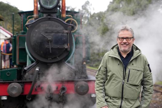 Philippe Gougler pose devant une locomotive à vapeur
