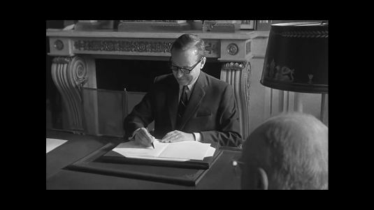 Michel Debré assis à son bureau, rédigeant un courrier