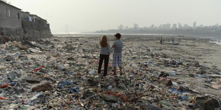 Bella et Vipulan de dos sur une plage indienne recouverte de déchets plastiques
